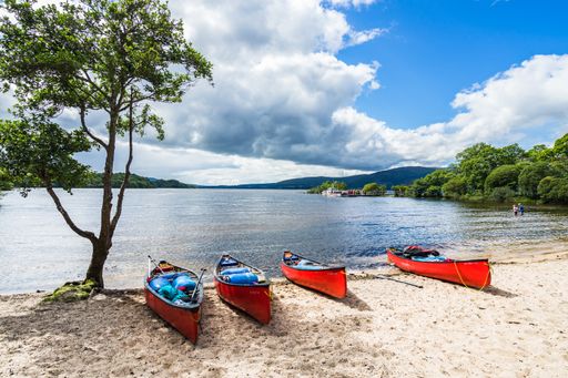 The red kayaks on a sandy beach in the summer in Loch Lomond, Scotland,