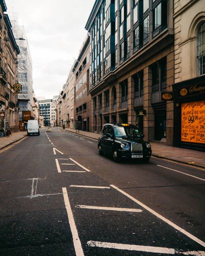 A vertical shot of a taxi driving on the streets of London, England
