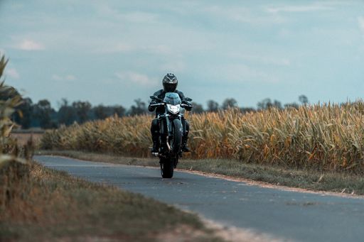 A man wearing a protective helmet on a black motorcycle traveling down a winding road