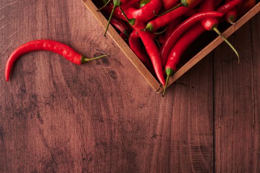 Several red chili peppers in a box put on a wooden surface