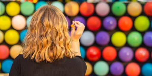 A female paying shooting range with colorful balloons at the amusement park