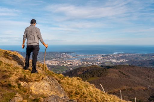 A young male looking at the views of the towns of Hondarribia and Hendaya from the mountains of Aiako Harriak, Spain