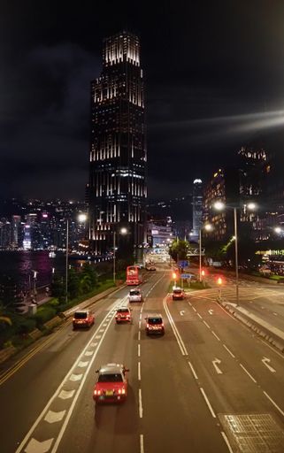 A busy nighttime highway scene in the vibrant city of Hong Kong, with a variety of cars traveling in both directions