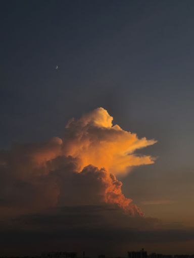 A beautiful sunset with a cloud illuminated by the warm orange and pink hues of the setting sun