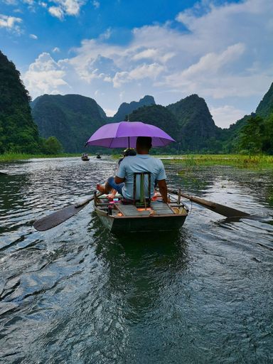 The tourists on a boat ride along a river surrounded by mountains in Ninh Binh, Vietnam