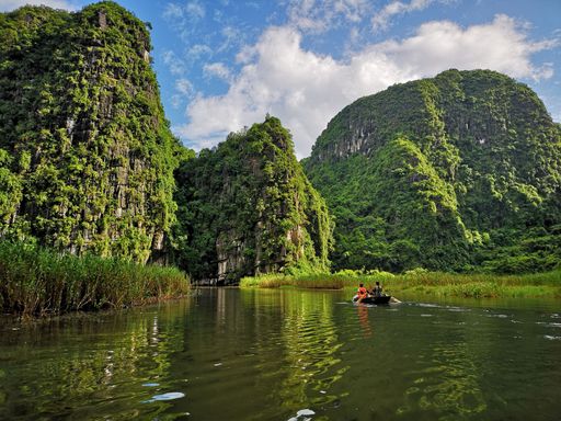 The tourists on a boat ride along a river surrounded by mountains in Ninh Binh, Vietnam