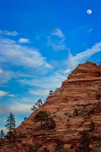Aerial view of the moon in the night sky above a mountain range in Zion National Park, Utah