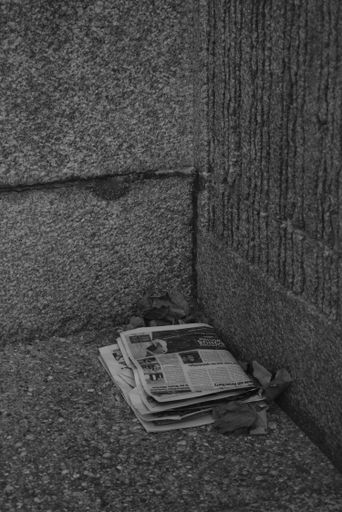 A newspaper is displayed on a concrete ledge in a room