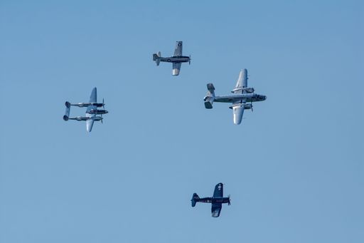 A low angle of airplanes flying in the blue sky during a show