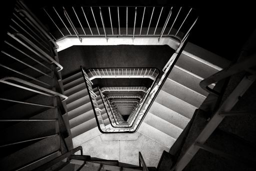 A top view of a modern spiral staircase leads to the upper levels of a building