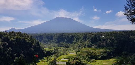 Majestic great mountain volcano called Gunung Agung. In tranquil forest with panoramic sky.