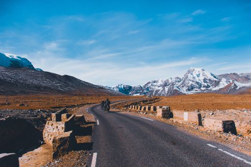 The motorbikers on a narrow road through snowy mountains