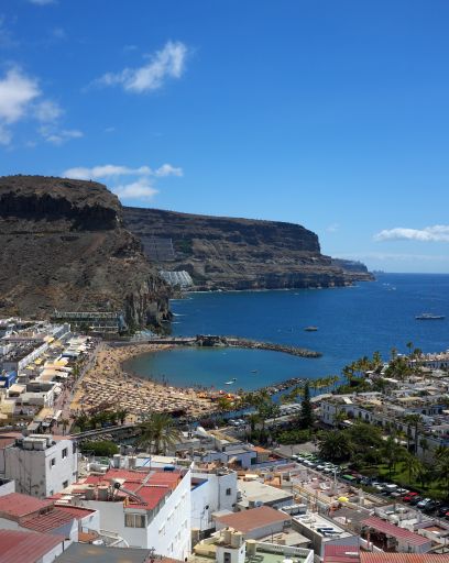 Aerial view of Playa de Mogan, in Gran Canaria, Spain, one of the Canary Islands. Image shows buildings, beach, bay, sea and nearby hills on the coast