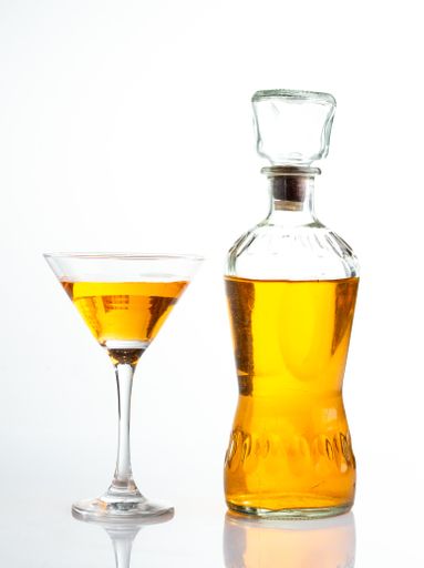 A vertical shot of a glass of whiskey next to a full glass bottle isolated on whi