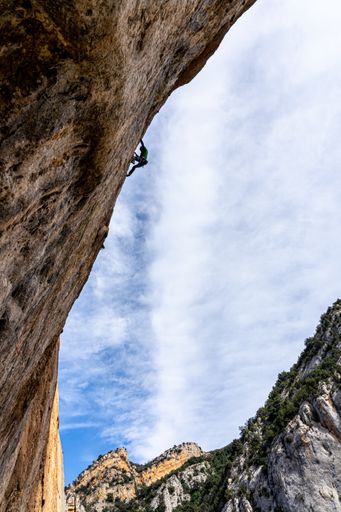 A vertical shot of an alpinist climbing up a steep mountain