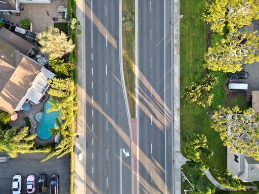 Aerial view of a cityscape featuring multiple buildings in the skyline, a road and road lines. Street and homes.