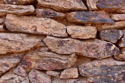 Various reds, browns, and blacks make up a colorful old rock wall.