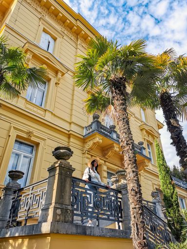 Young woman standing on a balcony of a old building in coastal  summer resort in Opatija, Croatia.