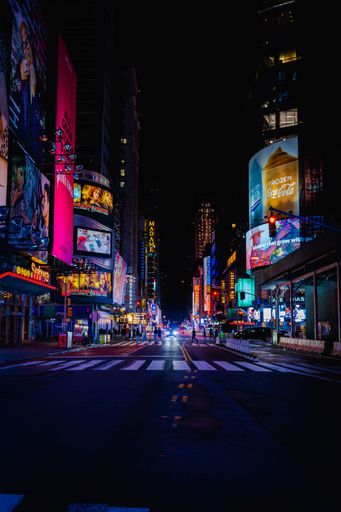 An urban street scene at night featuring multiple parked cars alongside a lit crosswalk
