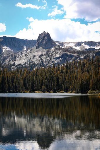 A vertical shot of the Mammoth Lakes in California, featuring rocky mountains and lush forest in the background