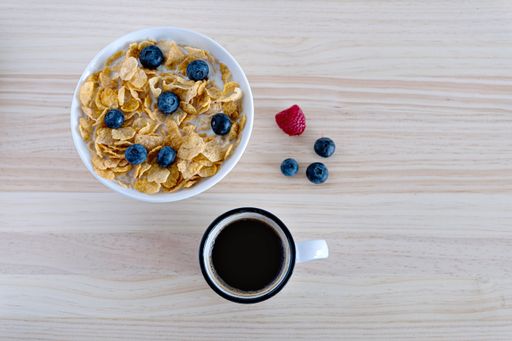 A top view of hot coffee and cereals with berries for breakfast