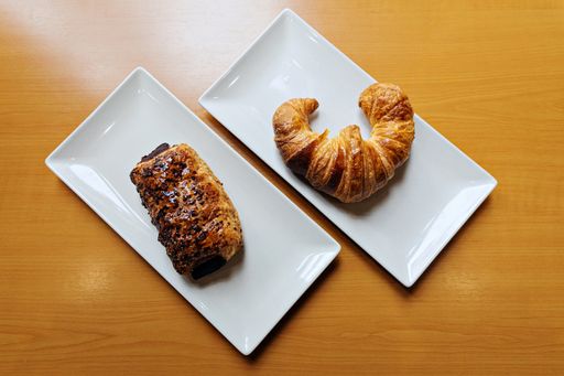 A top view of a fresh pastry and a croissant on plates
