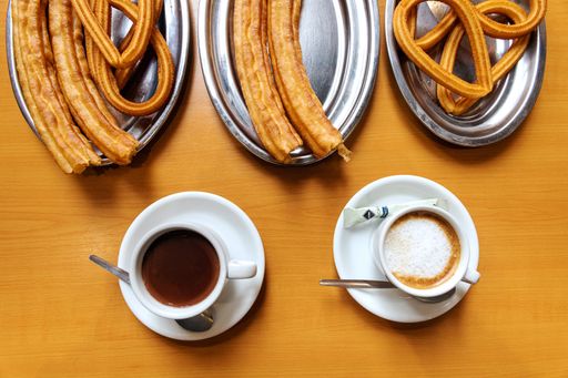 A high angle shot of delicious fresh churros and cups of coffee