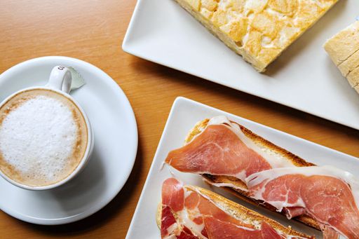 A top view of a cup of cappuccino with bread and ham