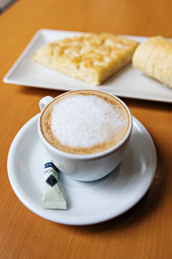 A selective focus of a cup of cappuccino on a background of cheese omelet on a plate