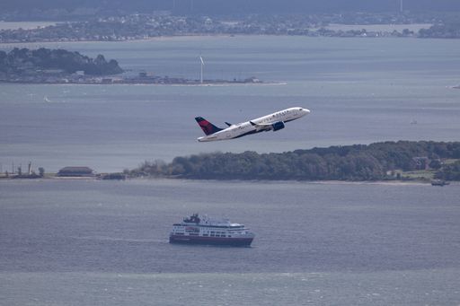 An airplane is soaring above a tranquil ocean landscape featuring a sailboat and a picturesque island in the background