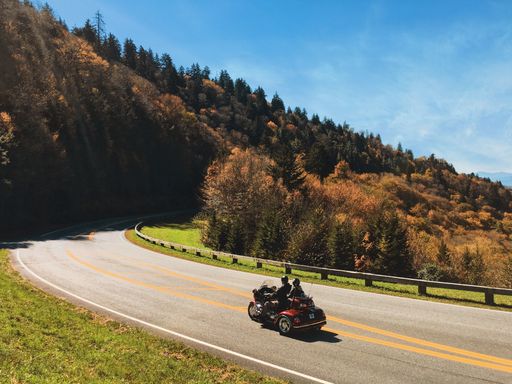 A motorcycle driving along a scenic road surrounded by lush green hills covered in trees
