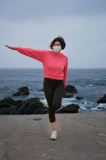 A Chilean woman with a mask doing relaxation exercises in front of the sea - New normality