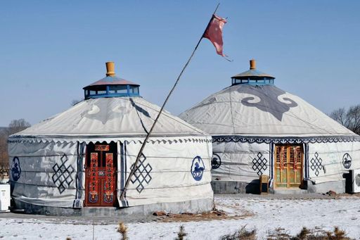 A picturesque winter scene of traditional Mongolian yurts dotting a pristine snow-covered landscape