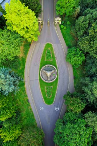 An aerial view of a scenic rural landscape featuring a road winding through lush green trees