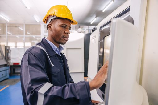 A male worker operating an automated machine in an industrial factory setting