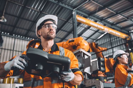 A group of industrial workers examining a machine in a factory setting