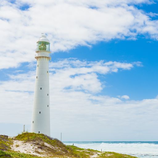 A scenic view of a lighthouse on the rugged Cape Town, South Africa coastline during the day