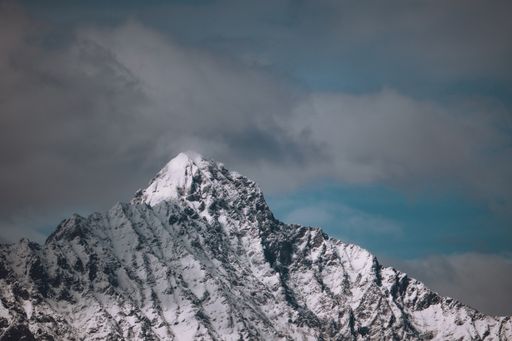 A beautiful scenery of a snow-covered rocky mountain under a cloudy sky
