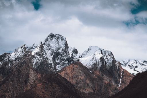 A beautiful scenery of snow-covered rocky mountains under a cloudy sky