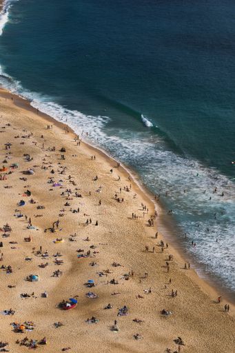 Aerial view of sunbathers and swimmers enjoying the beach at Praia de Nazare, Portugal