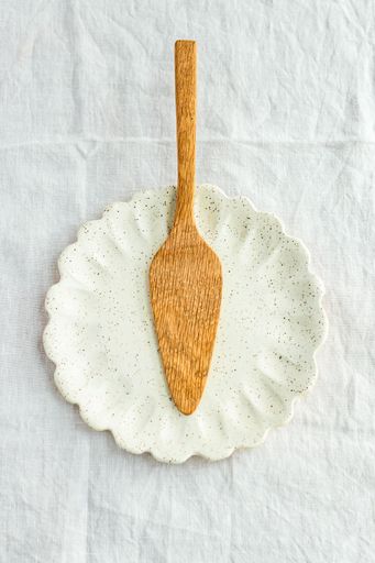 Handmade oak cake lifter on handmade ceramic scallop plate made with a speckle clay