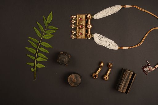 A top view of a beautiful necklace, earrings, a green leaf, and more on a dark surface