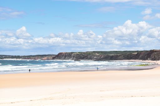 The surfers with surfboards on scenic Baleal beach near Peniche, Portugal