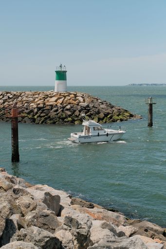 A majestic lighthouse stands amidst a rocky shoreline with a boat