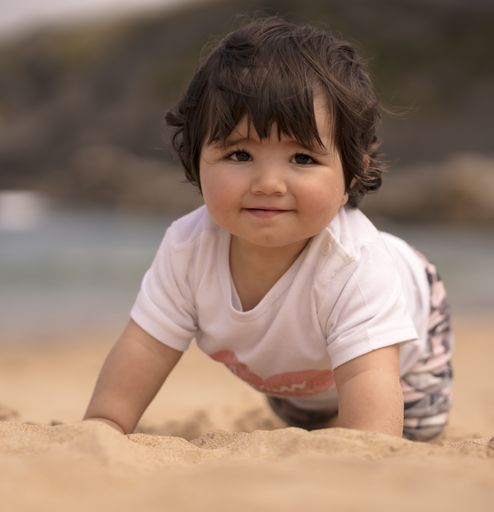 A cute Spanish baby playing on sandy beach