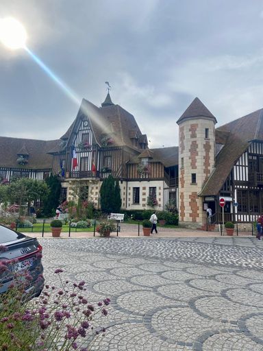 A majestic building with a stately tower in the center, set in front of a grand entrance gate adorned with intricate designs