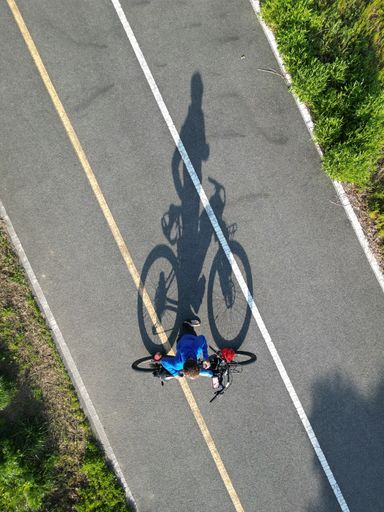 Two young male adults cycling side by side on a paved road, enjoying the outdoors
