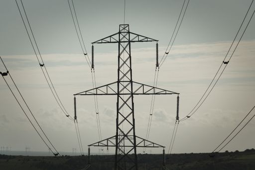 An aerial view of a series of high voltage electrical towers and power lines stretching across a landscape