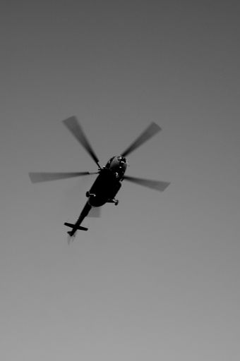 A vertical low angle shot of a helicopter in flight with clear sky in the background