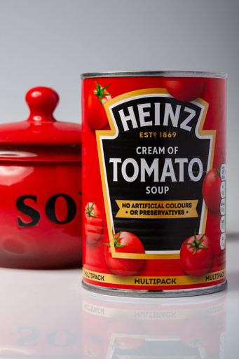 can of Heinz cream of tomato soup showing front of the label and the red soup bowl behind